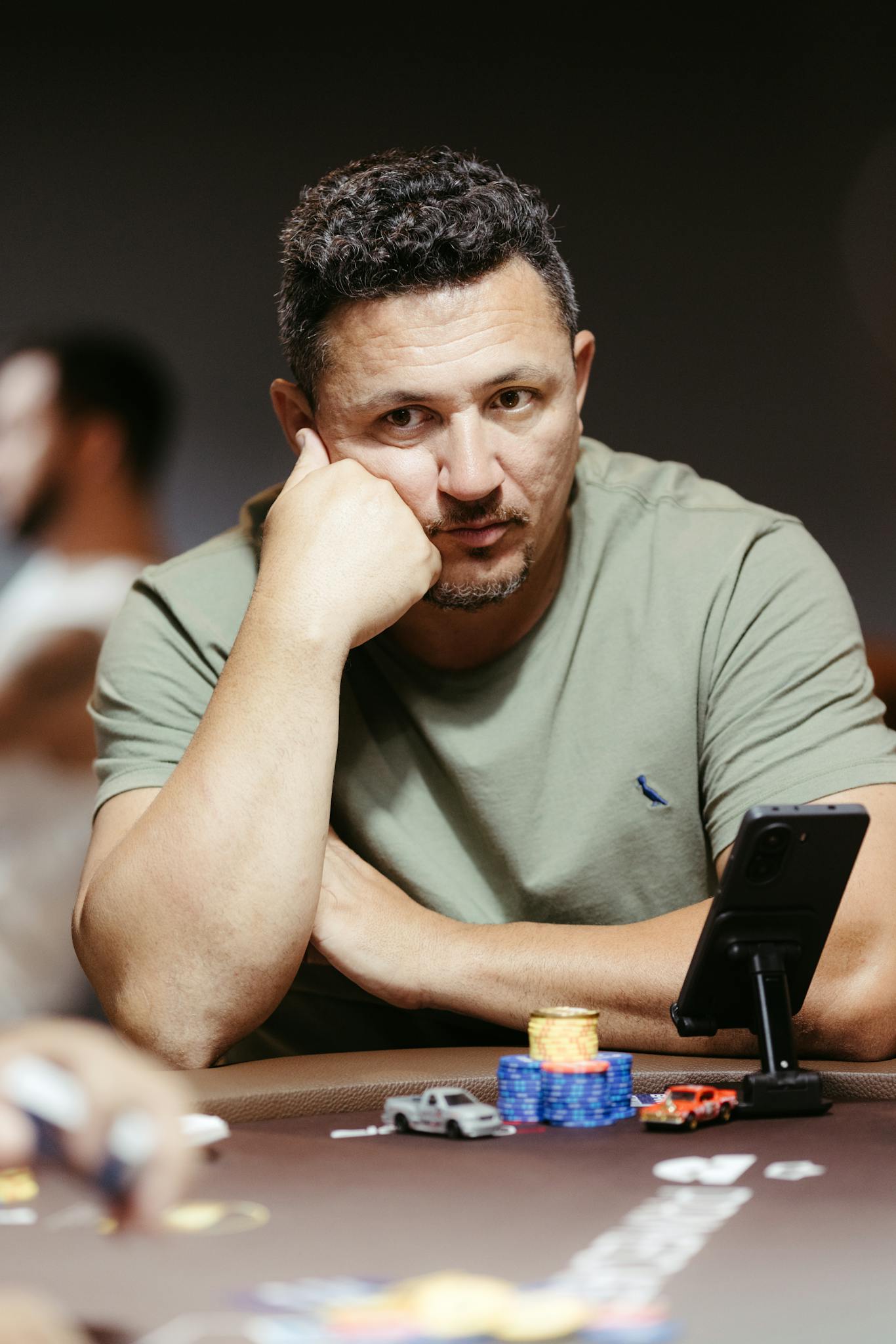 A man intensely focused during a poker game, surrounded by chips on a casino table.