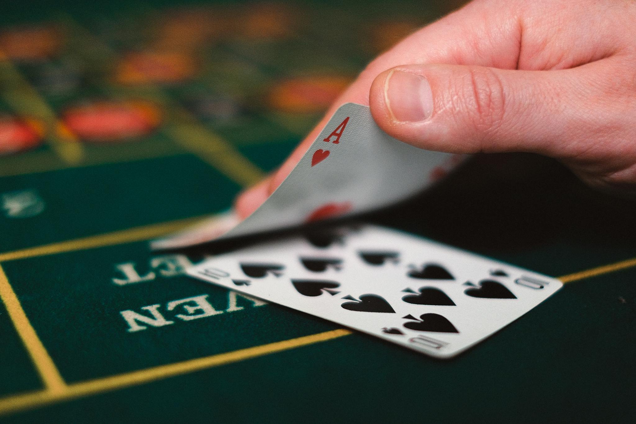 Close view of playing cards and hand on a casino table, capturing the gambling atmosphere.